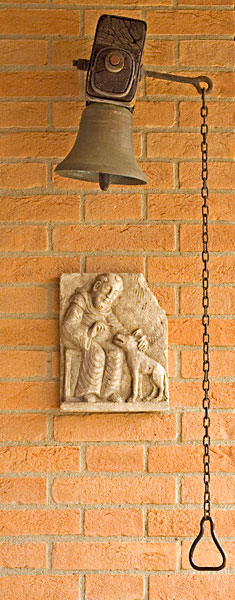 Bell at the welcoming area of the Monastery of Bose Bell and stone high-relief of St. Francis and the wolf